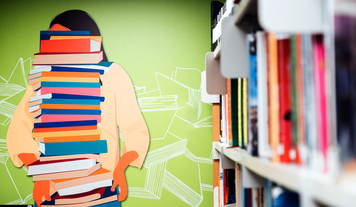A green wall with a drawing of a person holding books in various bright colours with bookshelves in the foreground