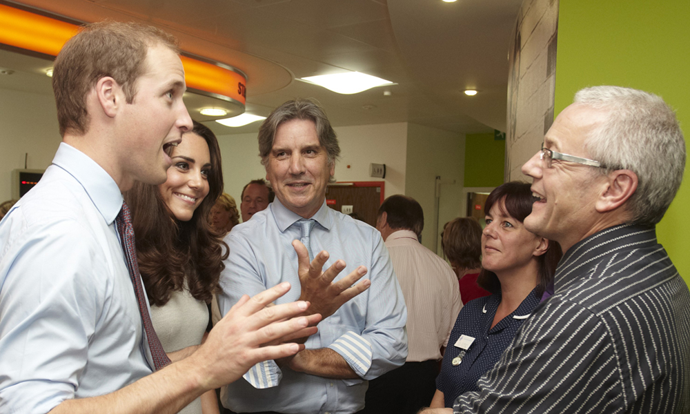 Prince William and Kate with a group of people talking to Colin Horn in a room.