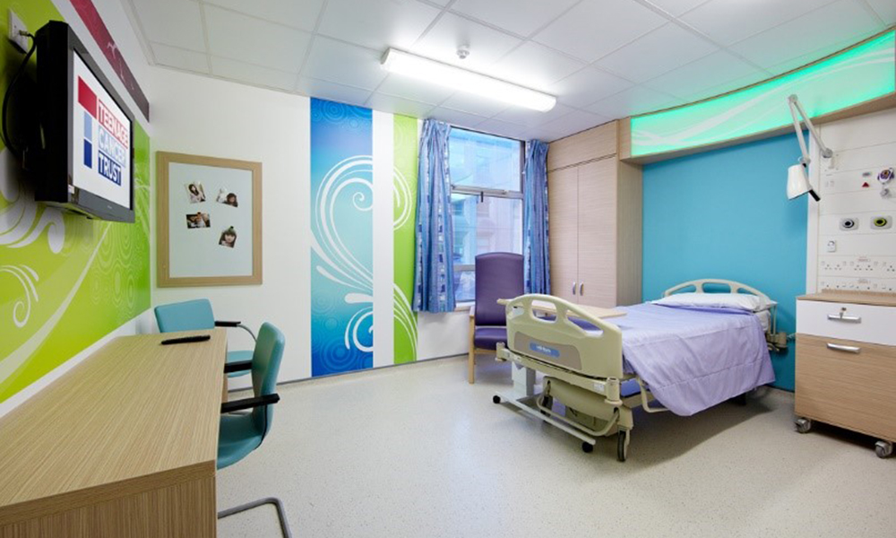 Teenage Cancer Trust hospital room with wall art and co-ordinating furniture including bed, chair and desk.
